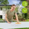 A young woman is cleaning a white table outdoors with a yellow cloth. There are icons in the upper right corner indicating cleaning and weather resistance. Náhľad obrázku produktu
