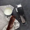 A hair clipper, comb, and balm are laid out on a dark surface with a cloth. Podgląd zdjęcia produktu