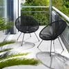 Two black Acapulco-style chairs on a balcony with plants and greenery in the background. Náhled obrázku produktu