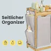 A close-up of a bamboo laundry organizer with side pockets and shelves, featuring various bottles and towels on the shelves. Produktbild-Vorschau