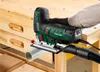 A person is using a jigsaw to cut a pipe on a workbench. Produktbild-Vorschau