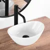 A white oval basin sink with a black faucet on a wooden countertop, with a mirror in the background. Náhled obrázku produktu