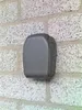A gray key safe is mounted on a textured brick wall. Produktbild-Vorschau