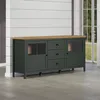 A dark green sideboard with a wooden top and glass cabinet doors sits in a room with white paneled walls and light gray flooring. Podgląd zdjęcia produktu