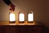 A hand is shown picking up one of three LED lanterns on a wooden surface. Produktbild-Vorschau