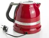 A red KitchenAid electric kettle with a black handle and a silver band around the base, shown on a white background with its power cord and plug visible. Produktbild-Vorschau
