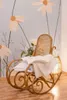 A rocking chair with a blanket and pillow is placed in front of a wall with a floral mural. A lamp is beside the chair. Produktbild-Vorschau