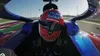 A first-person view from inside a race car, showing the driver's helmet and the track ahead. Náhled obrázku produktu