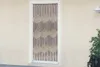 A beaded curtain hangs in a doorway against a textured wall. Produktbild-Vorschau