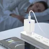 A person sleeping in bed while a phone and charger are plugged in and charging. Produktbild-Vorschau