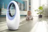 A baby is sitting on the floor next to a white and blue bladeless fan in a modern living room. Produktbild-Vorschau