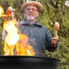 A man is grilling sausages over a fire. Produktbild-Vorschau