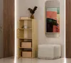 A hallway or entryway scene with a tall wooden cabinet, a mirror with abstract art, and a pouf. Anteprima dell’immagine prodotto