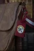 A close-up of a brown leather shoulder bag with a red luggage tag featuring the 'Platform 9 3/4' logo from Harry Potter. Anteprima dell’immagine prodotto