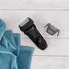 A black electric shaver with a grooming attachment and blue towels on a light wooden background. Anteprima dell’immagine prodotto