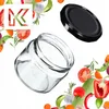 A clear glass jar and its black lid are shown against a white background, surrounded by various fresh vegetables and herbs. Produktbild-Vorschau