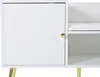 A close-up view of a white cabinet with a fluted door and a gold knob, next to an open shelf with a white cushion. The cabinet stands on gold metal legs. Produktbild-Vorschau
