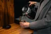 A person is pouring hot water from a black electric kettle into a glass with ice. Podgląd zdjęcia produktu