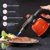 A hand holding a kitchen torch over a piece of meat on a plate, with salad in the background. Text overlays describe the torch's uses. Produktbild-Vorschau