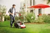 A man is mowing a lawn in front of a modern house. Náhľad obrázku produktu