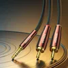 A close-up shot of a UGREEN audio cable with a 3.5mm jack and two RCA connectors, resting on a metallic surface resembling a vinyl record. Náhled obrázku produktu