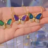 Drei goldene Ketten mit Schmetterlingsanhängern, jeder mit farbwechselnden Flügeln und Pavé-Kristallkörpern, in einer Hand gehalten Náhľad obrázku produktu