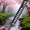 A close-up of a katana sword handle with a blurred background of a serene Japanese garden with cherry blossoms and a stream. Produktbild-Vorschau