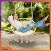 A woman is relaxing in a hanging chair outdoors, using a laptop. Produktbild-Vorschau