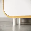 Close-up of the bottom of a white cabinet with rounded wooden trim, supported by white cylindrical legs on a concrete floor. Produktbild-Vorschau