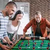 Three people are playing foosball in an office setting. Náhľad obrázku produktu