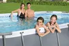 A family is enjoying themselves in an oval-shaped above-ground swimming pool in a backyard setting. Anteprima dell’immagine prodotto