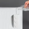 A hand is pouring water from a bottle into a white radiator humidifier with heart decorations. Voir les images du produit