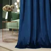 A close-up of a blue velvet curtain in a room with a green chair and a decorative table. Anteprima dell’immagine prodotto