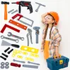 A young girl wearing a hard hat and an orange shirt is looking up and to the side, surrounded by a collection of toy tools and a toolbox. Produktbild-Vorschau