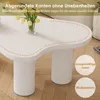 A close-up view of a white, cloud-shaped coffee table with yellow tulips in a vase. Produktbild-Vorschau