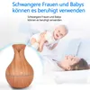 A woman and baby are lying on a bed, with a humidifier in the foreground. Produktbild-Vorschau