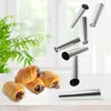 A product shot of baking molds and filled pastries, with a blurred green plant and window in the background. Podgląd zdjęcia produktu