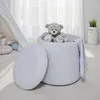 A child's room with a teddy bear sitting in a white storage ottoman. Náhled obrázku produktu