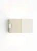 A modern, beige LED wall light mounted on a white wall, with light emanating from the bottom. Anteprima dell’immagine prodotto