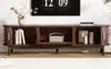 A dark brown TV stand with decorative items and books on it, placed in a room with a large digital clock on the wall above it. Produktbild-Vorschau