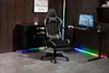 A gaming chair and desk setup in a modern room with wood paneling and RGB lighting. Produktbild-Vorschau