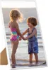 Two children standing in shallow water at the beach, holding hands. Náhľad obrázku produktu