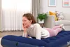 A woman is lying on a blue air mattress in a living room. Náhled obrázku produktu