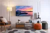 A living room scene with a TV mounted on the wall, a floor lamp, an armchair, a media console, and decorative items. Voir les images du produit