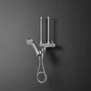 A chrome shower mixer tap with a hand shower attachment is mounted on a dark gray wall. Produktbild-Vorschau
