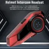 A red and black helmet intercom headset is displayed against a dark, abstract background with geometric shapes and lighting effects. Náhled obrázku produktu