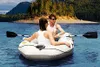 A couple is rowing an inflatable boat on a lake with a forested mountain in the background. Anteprima dell’immagine prodotto