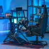 A gaming setup with a racing wheel stand, chair, and desk, illuminated by blue LED lights. Produktbild-Vorschau