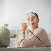 A woman is meditating with incense burning in front of a Buddha statue. Podgląd zdjęcia produktu
