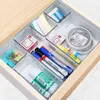An open drawer filled with clear plastic organizers containing various stationery items. Náhled obrázku produktu